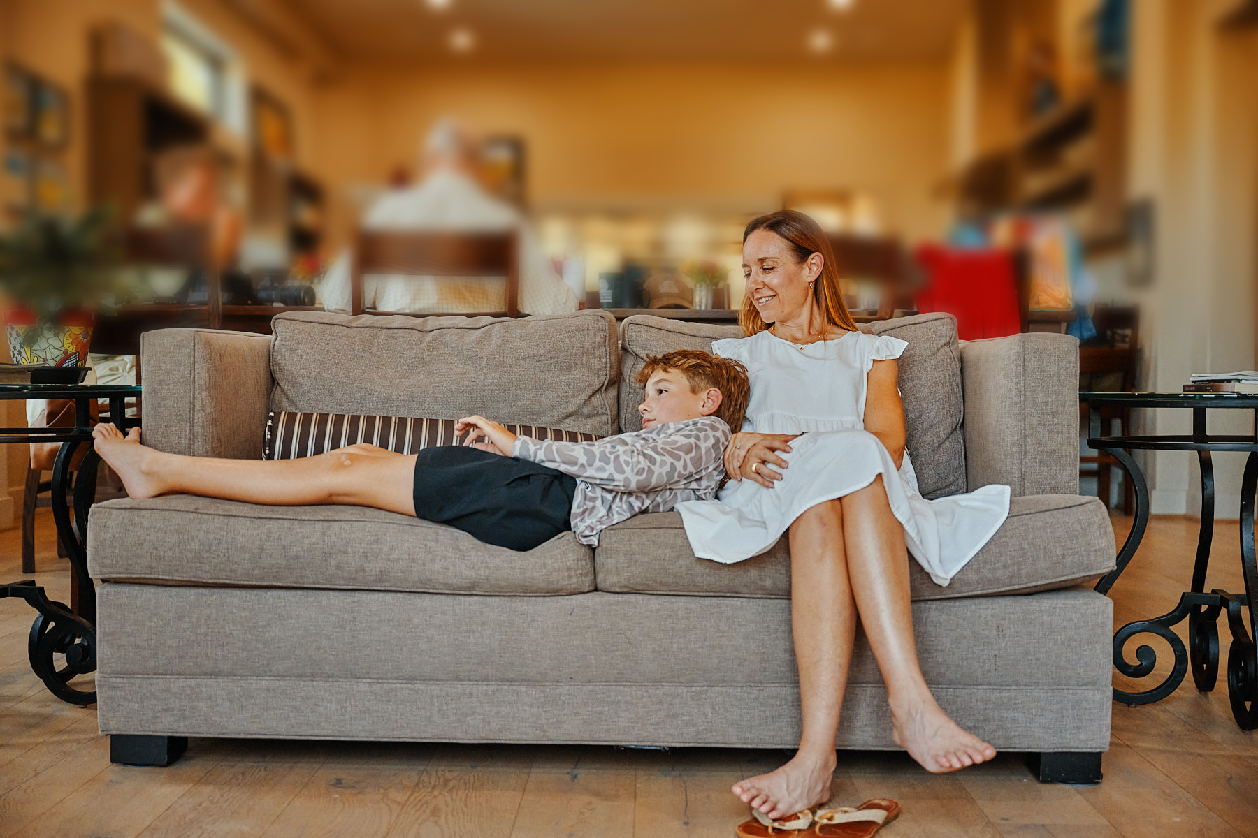 Mother and son relaxing together on a comfortable sofa inside a Whispering Trees Farm cottage,